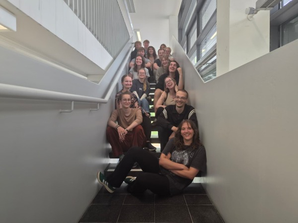 Die Mitglieder des neugewählten Fachschaftsrat für Naturwissenschaften sitzen lächelnd auf einer Treppe in Gebäude 22.